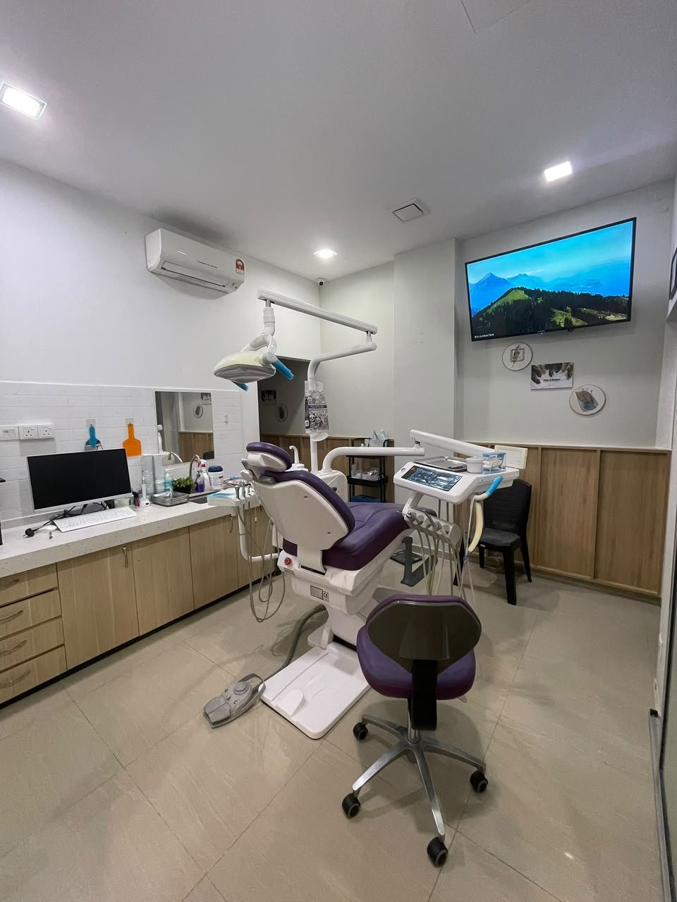 AN NAJAH treatment room with a purple dental chair and timber cabinetry